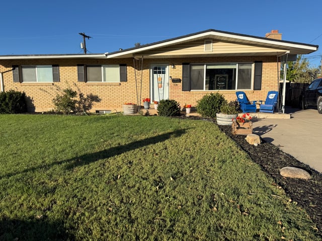 Fresh curb appeal at 396 W 1130 N with green lawn, colorful flowers, and covered front porch